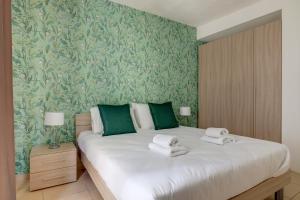 a bedroom with a large white bed with green wallpaper at Sliema Tigne Suites in Sliema