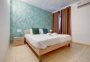 a bedroom with a large bed with green wallpaper at Sliema Tigne Suites in Sliema