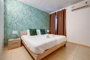a bedroom with a large bed with green wallpaper at Sliema Tigne Suites in Sliema