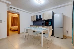 a kitchen with a table with chairs and a refrigerator at Sliema Tigne Suites in Sliema