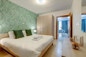 a bedroom with a large white bed with green wallpaper at Sliema Tigne Suites in Sliema