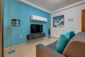 a living room with a couch and a tv on a blue wall at Sliema Tigne Suites in Sliema