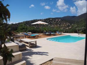 - une piscine avec des chaises, une table et un parasol dans l'établissement RÊVE DE MER, à Cavalaire-sur-Mer