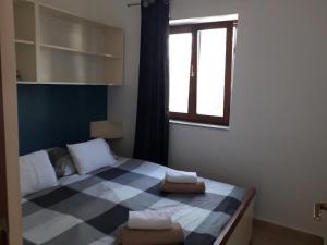a bedroom with a checkered bed with two towels on it at Apartmani Zdenka Savar-Maslina in Savar