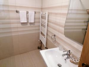 a white bathroom with a sink and a mirror at Cozy attic studio in Braşov +13 photos