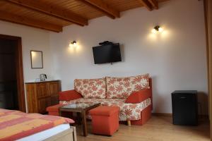 a living room with a couch and a tv on the wall at Penzion Úsmev in Arnutovce
