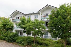 a white building with trees in front of it at Appartement Granitz - Ferienwohnung Thoenissen in Göhren