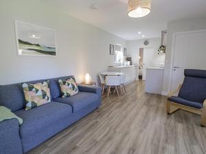 a living room with a blue couch and a kitchen at Dinas Lodge in Caernarfon