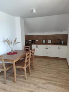 cocina con mesa de madera y sillas en una habitación en Apartament za lasem, en Kaliska Kośierskie