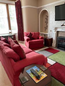 a living room with a red couch and a fireplace at Inchrye Bed & Breakfast in Inverness