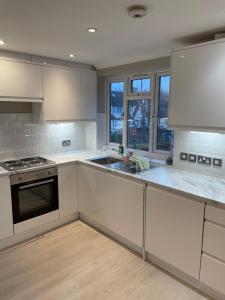 a kitchen with white cabinets and a sink at Super Convenient 2 Double Bed apartment for Central London - 30 seconds walk to platform train station and 19 mins to London Waterloo in London