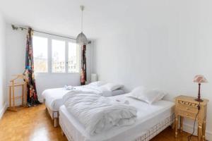 a white bedroom with two beds and a window at HSH Saint-Charles André-Citroën Superbe appartement 5P in Paris