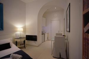 Dieses weiße Zimmer verfügt über ein Bett, einen Schreibtisch und einen TV. in der Unterkunft Aureliana Apartments in Rom