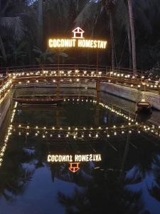 a swimming pool with lights in front of a sign at Coconut Homestay Mỏ Cày Nam Bến Tre in Ben Tre