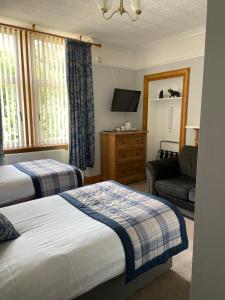 una camera d'albergo con due letti, un divano e una TV di Inchrye Bed & Breakfast a Inverness