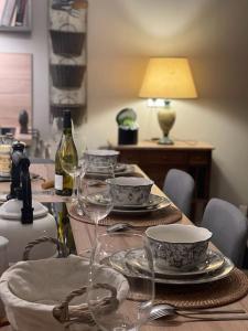 a table with glasses and plates and a bottle of wine at Le pigeonnier / Gîte de charme 1 à 4 pers 80 m² in Cambrai