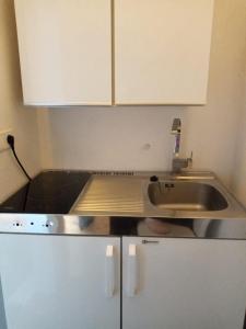 eine kleine Küche mit einem Waschbecken und weißen Schränken in der Unterkunft Pension Reiter in Blomberg