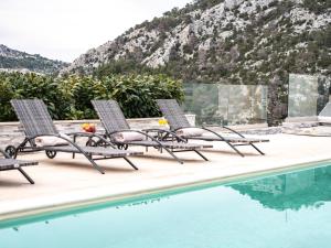 a group of lounge chairs next to a swimming pool at Elegant Hvar town villa with pool in Hvar