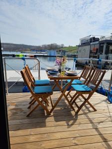 einen Holztisch und Stühle auf einer Terrasse mit einem Boot in der Unterkunft Mobiles Hausboot El'milia in Braunsbedra