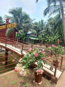 ベンチェにあるCoconut Homestay Mỏ Cày Nam Bến Treの花の置かれた公園のベンチとホテルの看板