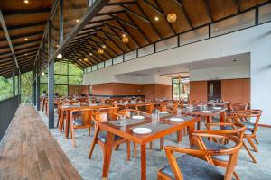 une salle à manger avec des tables et des chaises en bois dans l'établissement Crystal Kuruva Nature Resort & Spa, à Wayanad