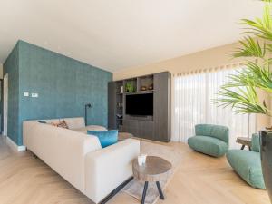 een woonkamer met een witte bank en een tv bij Modern water villa in Zeewolde with jetty in Zeewolde