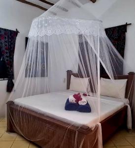 a bed with a canopy with towels on it at Villa Kikadini in Jambiani