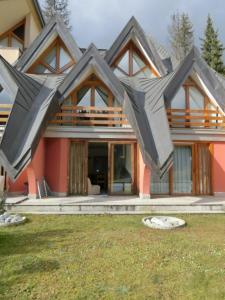 a house with a large roof on top of it at Alberti - Condominio Villa Golf in Madonna di Campiglio