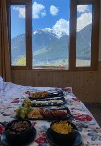 una mesa con platos de comida en una cama con ventana en Spire View en Manāli