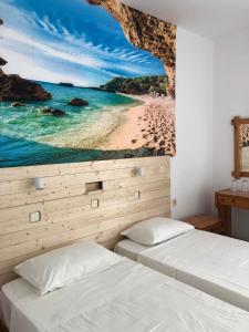 a bedroom with two beds and a painting of a beach at Antonis Hotel in Kefalos