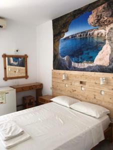 a bedroom with a bed with a painting on the wall at Antonis Hotel in Kefalos