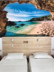 two beds in a room with a view of a beach at Antonis Hotel in Kefalos