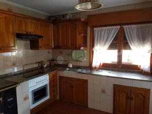 cocina con armarios de madera, fregadero y ventana en La casa de Carolina, en Onís