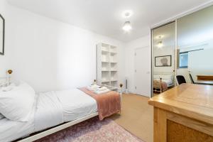 een witte slaapkamer met een bed en een bureau bij Contemporary Top floor flat in Kentish Town in Londen