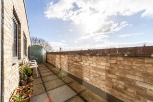 een bakstenen muur naast een gebouw met een patio bij Contemporary Top floor flat in Kentish Town in Londen