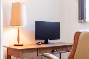 a desk with a computer monitor and a lamp on it at Contemporary Top floor flat in Kentish Town in London