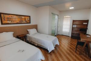 a hotel room with two beds and a table at Hotel Fazenda Bona Espero in Alto Paraíso de Goiás