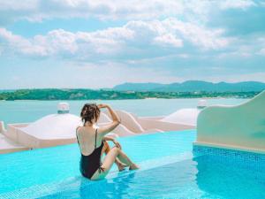 a woman sitting on the edge of a swimming pool at Yuki Suite Kourijima in Nakijin