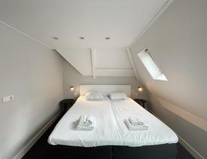 a bedroom with a white bed with towels on it at Hello Zeeland - Appartement Markt 5 en 5A in Domburg