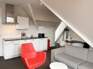 a living room with a couch and a red chair at Hello Zeeland - Appartement Markt 5 en 5A in Domburg