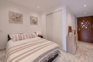 een witte slaapkamer met een bed en een houten deur bij Studio Menton Garavan avec piscine à proximité Italie et Monaco in Menton +24 foto's
