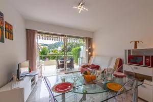 een woonkamer met een glazen tafel en een bank bij Studio Menton Garavan avec piscine à proximité Italie et Monaco in Menton