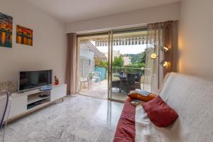 een woonkamer met een bank, een televisie en een balkon bij Studio Menton Garavan avec piscine à proximité Italie et Monaco in Menton