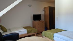 Habitación pequeña con 2 camas y TV. en Gasthof zum Lehnerwirt, en Breitenbrunn
