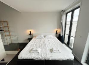 a bedroom with a large white bed with towels on it at Hello Zeeland - Appartement Markt 4 en 4A in Domburg