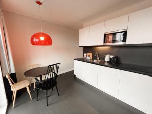 a kitchen with white cabinets and a table and chairs at Hello Zeeland - Appartement Markt 4 en 4A in Domburg