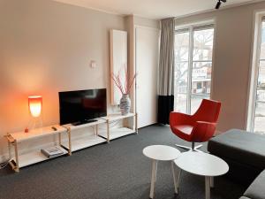 a living room with a television and a red chair at Hello Zeeland - Appartement Markt 4 en 4A in Domburg