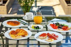 a table with plates of breakfast foods and a glass of orange juice at Sierra Blanca Resort and Spa in Marbella