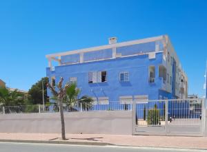 a blue building with a palm tree in front of it at HomeXperience in San Pedro del Pinatar