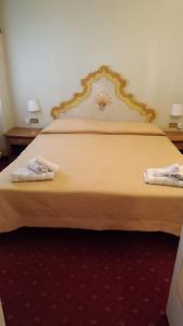 a bedroom with a large bed with two towels on it at Hotel Posta R.T.A. in Madonna di Campiglio